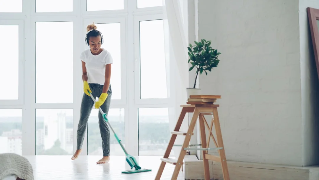 Woman wrapping a sofa with plastic for moving in a bright living room.