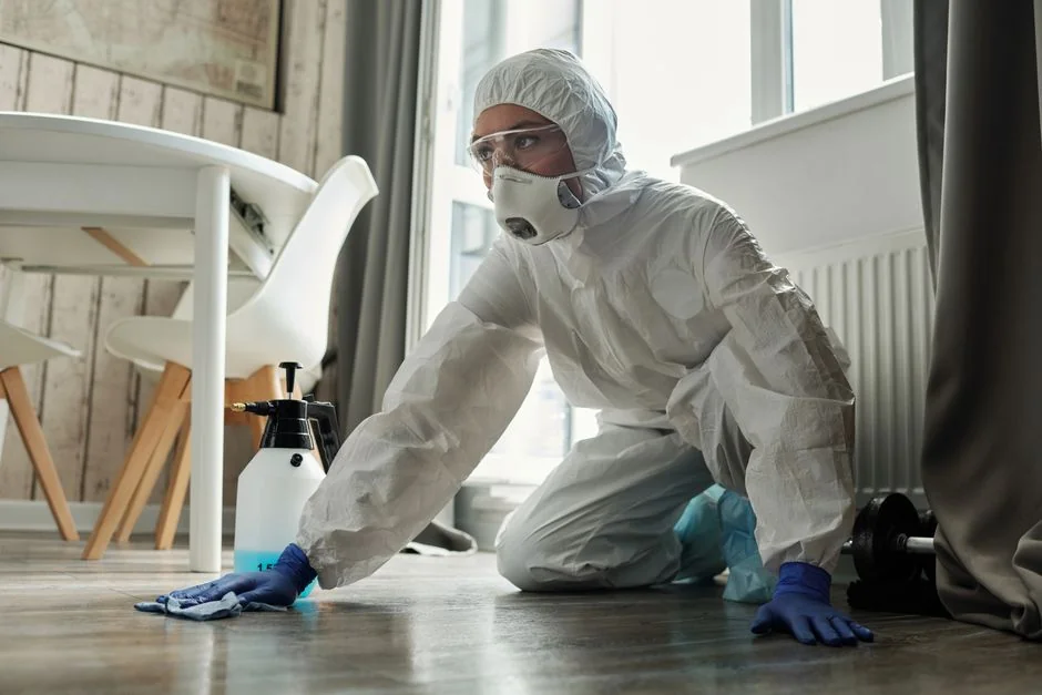 A woman carefully covers a sofa with protective material while packing boxes in a bright room.